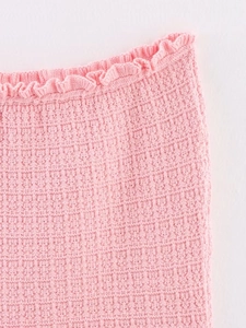 Macro view of pink knitted fabric detail with elegant ruffled edges and soft texture