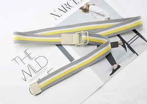 Close-up of striped canvas belt with grey, yellow, and white patterns and D-ring buckle