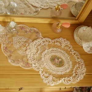 Vintage beige lace placemat with floral embroidery on a warm wooden tabletop