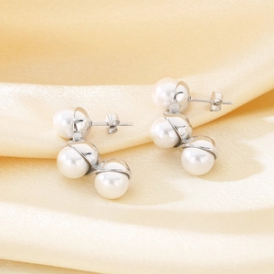 Close-up of elegant C-shaped silver earrings featuring three vertical pearls on silk