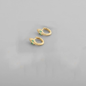 Close-up of golden snake hoop earrings with green gemstone eyes and scale details