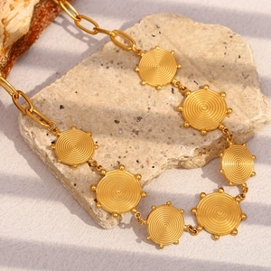 Detailed close-up of a 18K gold plated spiral pendant with oval chain links on stone