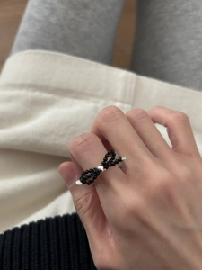 Detail of handcrafted black beaded bow ring with silver center bead on finger