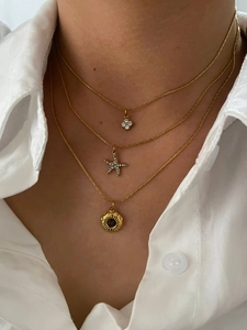 Detailed view of layered gold necklace with four-petal flower and starfish pendants