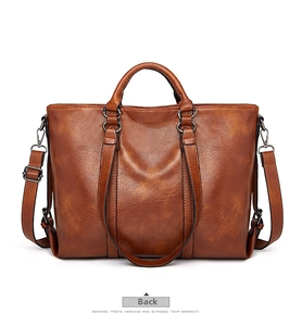 Dettaglio della borsa tote in pelle cerata marrone con manici rinforzati e fibbie in metallo