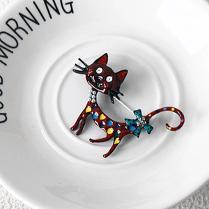Detail of red enamel cat brooch with colorful spots, faux pearls and rhinestone bow