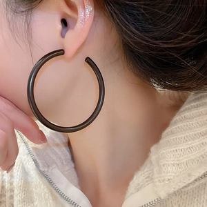 Close-up of minimalist black matte acrylic large hoop earrings on model for daily wear