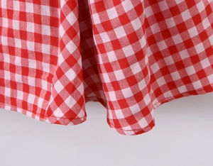 Gros plan sur le motif vichy rouge et blanc et les coutures de l'ourlet de la robe