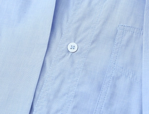 Close-up of light blue shirt showing fine fabric texture and white button stitching