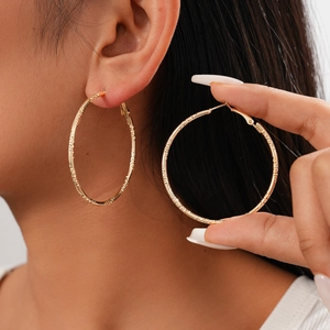 Detail showing textured gold hoop earrings on a model for a stylish minimalist look
