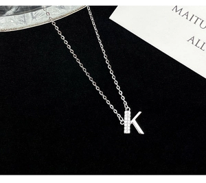 Macro shot of S925 silver letter K necklace with zircon inlay on black velvet
