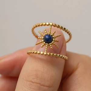 Detail of double-row gold star ring with blue gemstone inlay and beaded texture
