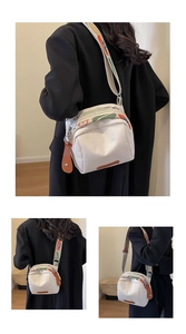 Detailed view of white canvas crossbody bag with colorful wide strap and leather accents