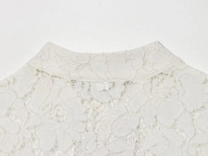 Dettaglio del colletto in pizzo bianco con ricami floreali ed elegante bottone a rana