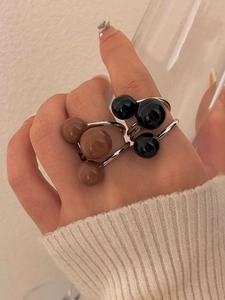 Detailed close-up of a three-ball cartoon silhouette ring worn on a finger