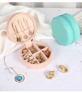 Detail view of round portable jewelry box with zipper and removable dividers in pink and green