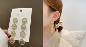 Detailed view of long gold tassel earrings with zircon butterflies on a display card
