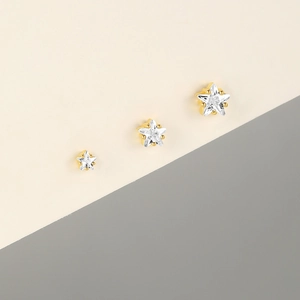 Macro detail of three sizes of star-shaped silver earrings with sparkling white zircons