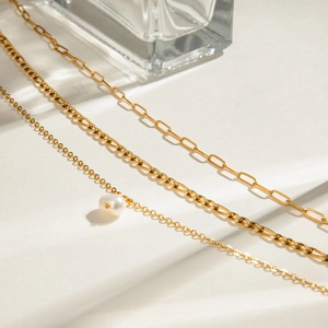 Detailed view of layered gold necklace set with freshwater pearl and paperclip chain