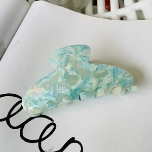 Close-up of blue and white marble acetate hair claw clip with pearlescent finish