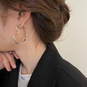 Boucles d'oreilles créoles cœur argentées portées par un mannequin en blazer noir