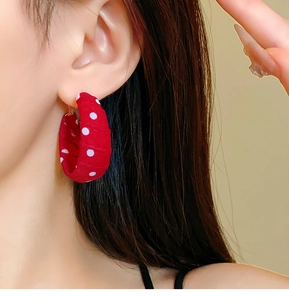 Close-up of vintage red fabric hoop earrings with white polka dots worn by a model