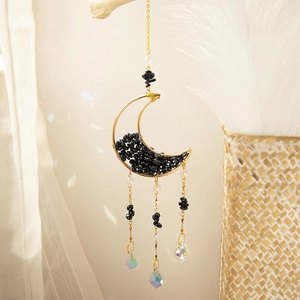 Detail of moon-shaped gold suncatcher featuring black crushed stones and crystal prisms