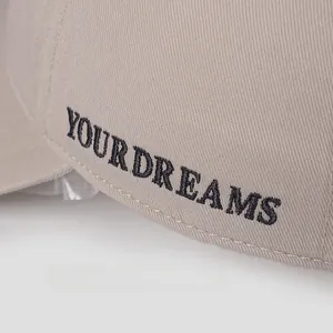 Macro detail of YOUR DREAMS black embroidery on beige cotton twill baseball cap
