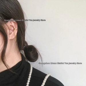 Close-up of golden heart chain ear cuff with long tassel fringe on earlobe