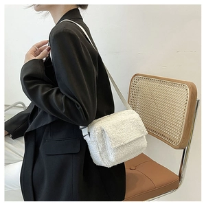 Detail of white plush crossbody bag worn with a black blazer on a professional model