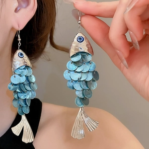 Detailed close-up of large fish-shaped drop earrings with blue scales and silver accents