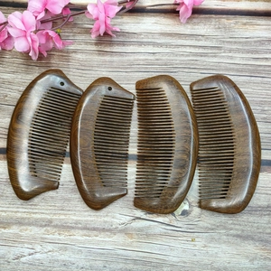 Close-up of four smooth black sandalwood combs with natural wood grain on wood background