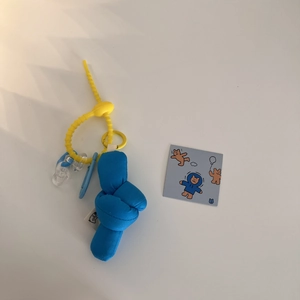 Close-up of royal blue fabric knot bag charm with yellow ring and cute bear tag