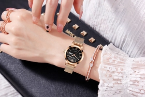 Elegant rose gold mesh strap watch with black dual-calendar dial worn by model