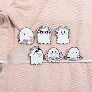 Close-up of seven cute pink and white ghost enamel pins on pink fabric texture