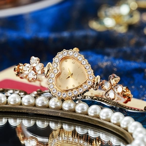 Macro shot of gold heart watch with clover crystals on a vintage mirror surface