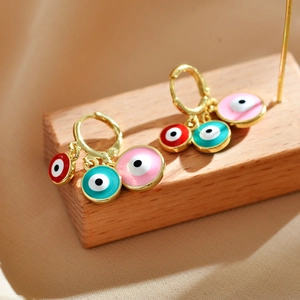 Bohemian gold earrings with three colorful evil eye enamel charms on wooden base