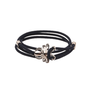 Macro shot of dark blue braided cord bracelet with silver octopus charm and metal clasp