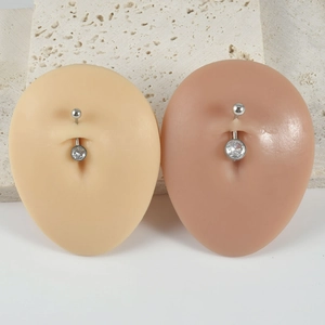 Macro shot of silver navel rings with clear zircon on silicone belly models