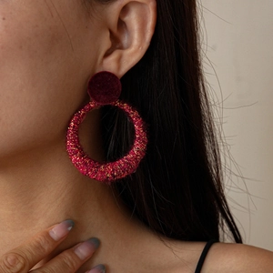 Close-up of a model wearing deep pink flocked circular earrings with gold metallic fibers