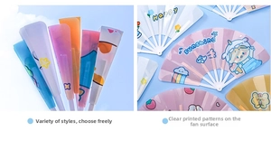 Detail of colorful foldable plastic hand fans featuring cute cartoon patterns and rainbow designs