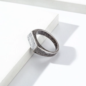Close-up of minimalist silver signet ring with vintage finish on geometric base