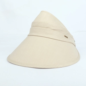 Detail of beige sun visor with wide brim and small gold metal logo on breathable fabric