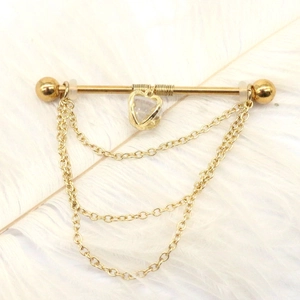 Detail of gold industrial barbell with heart-shaped stone and triple chain tassel over white feathers