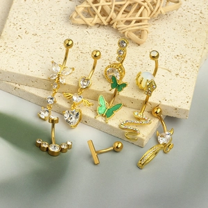 Flat lay of gold navel rings featuring butterfly, snake, and zircon heart charms