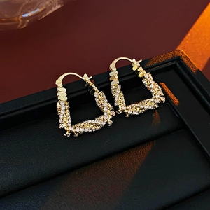 Detailed shot of gold U-shaped earrings featuring paved sparkling zircon stones on leather