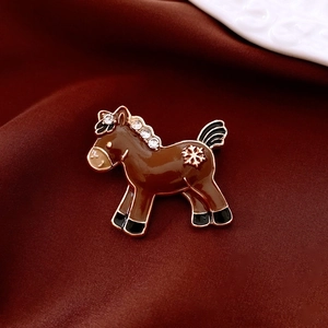 Macro detail of vintage horse brooch with brown enamel, gold snowflakes and white zircons