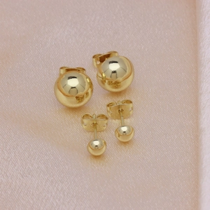 Minimalist 18k gold plated round ball stud earrings in two sizes on pink silk