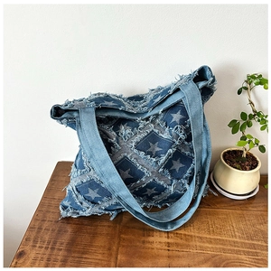 Detail of star pattern patchwork and frayed edges on denim tote bag over a wooden table