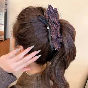 Plaid fabric hair scrunchie with black ribbon bow and diamond detail on model ponytail
